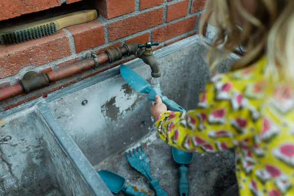 Rutabaga Garden Tools designed for small hands. Child is washing the garden tools in an outdoor sink.